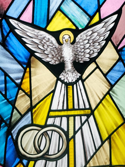 Image of the Holy Spirit in front of Stained Glass window about a Cross and entwined wedding bands